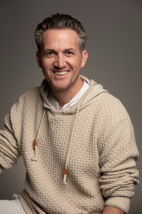 Matthew Dearing in a cream knit sweater, smiling, studio portrait by Brad Reed, 2025.